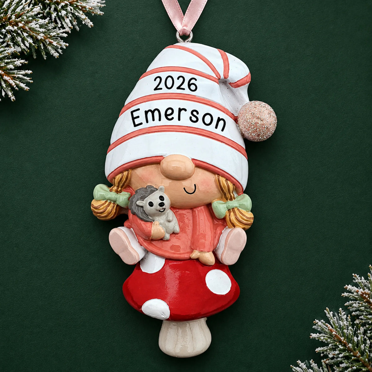 Personalized baby girl gnome christmas ornament on a dark green pine background