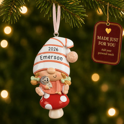 Baby girl gnome christmas ornament hanging on a lit Christmas tree with a Made Just For You gift tag
