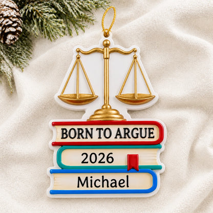 Personalized Born to Argue lawyer christmas ornament laid on a soft white knit blanket
