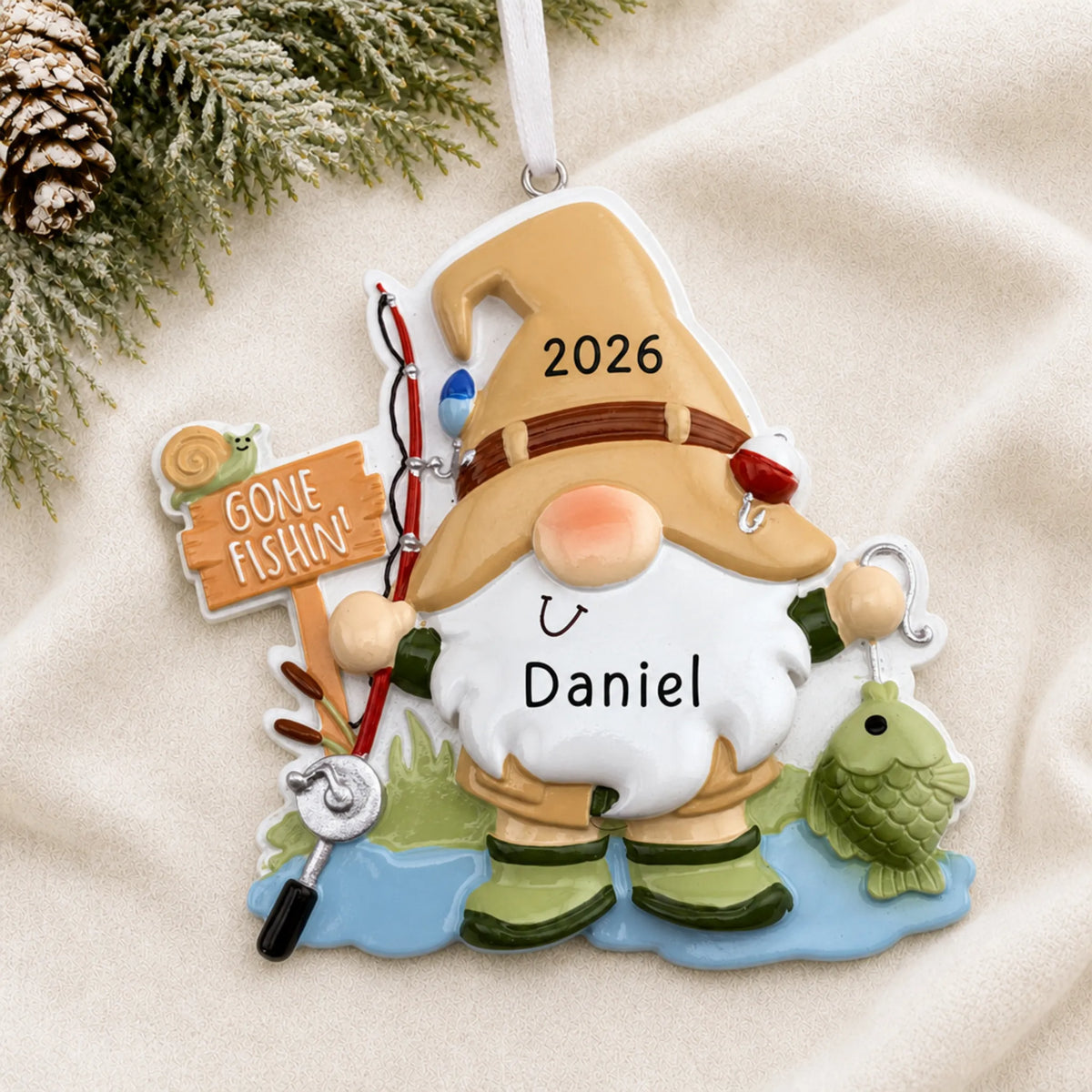 Personalized gnome fisherman christmas ornament laid on a soft white knit blanket