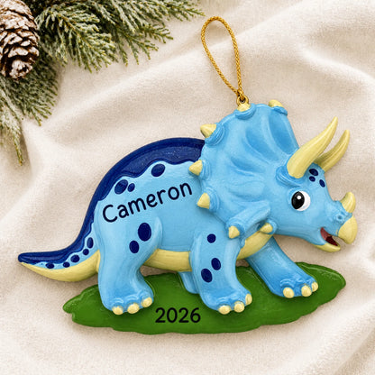 Personalized blue triceratops dinosaur christmas ornament laid on a soft white knit blanket