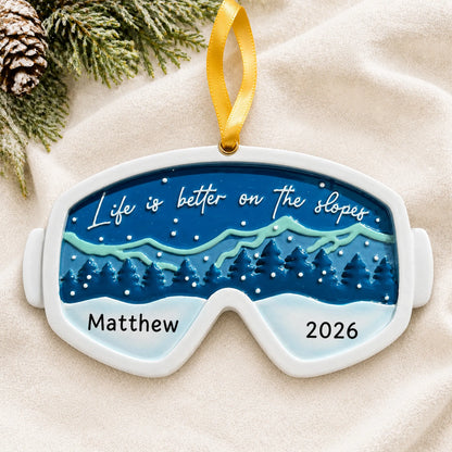 Personalized ski goggles christmas ornament laid on a soft white knit blanket
