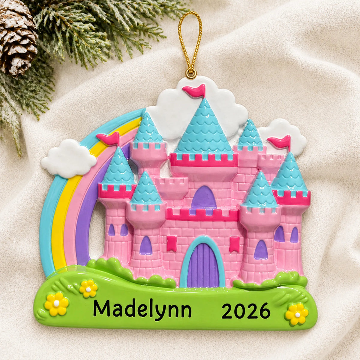 Personalized princess rainbow castle christmas ornament laid on a soft white knit blanket