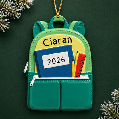 Personalized green school backpack Christmas ornament with name and year, shown on a green holiday background