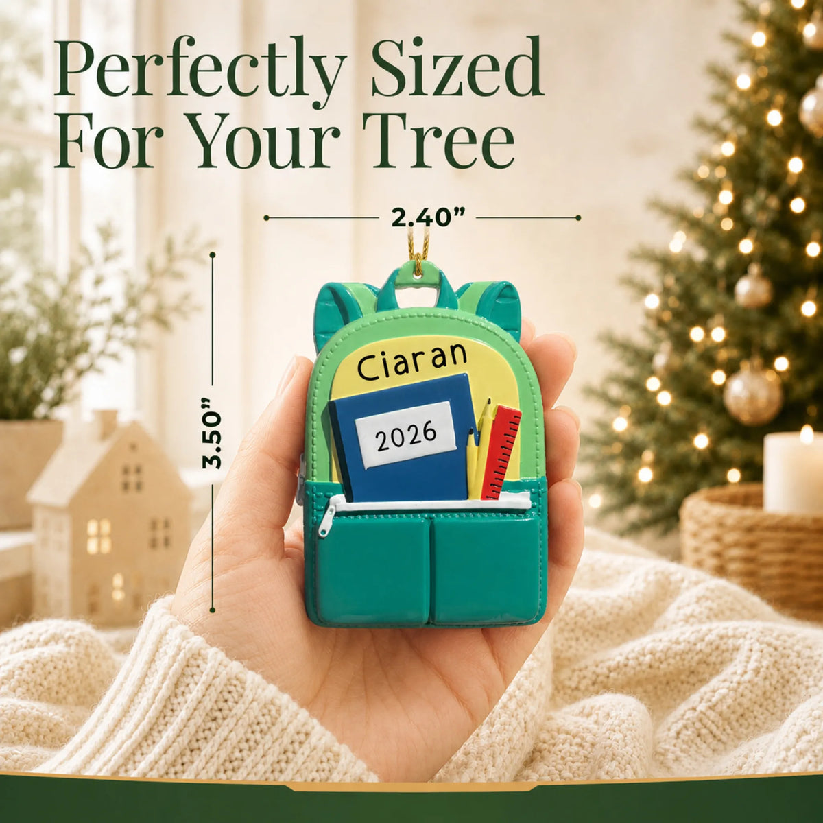 Personalized green school backpack Christmas ornament held in hand to show its size on the tree
