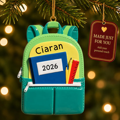Personalized green school backpack Christmas ornament hanging among tree lights with a Made Just For You tag