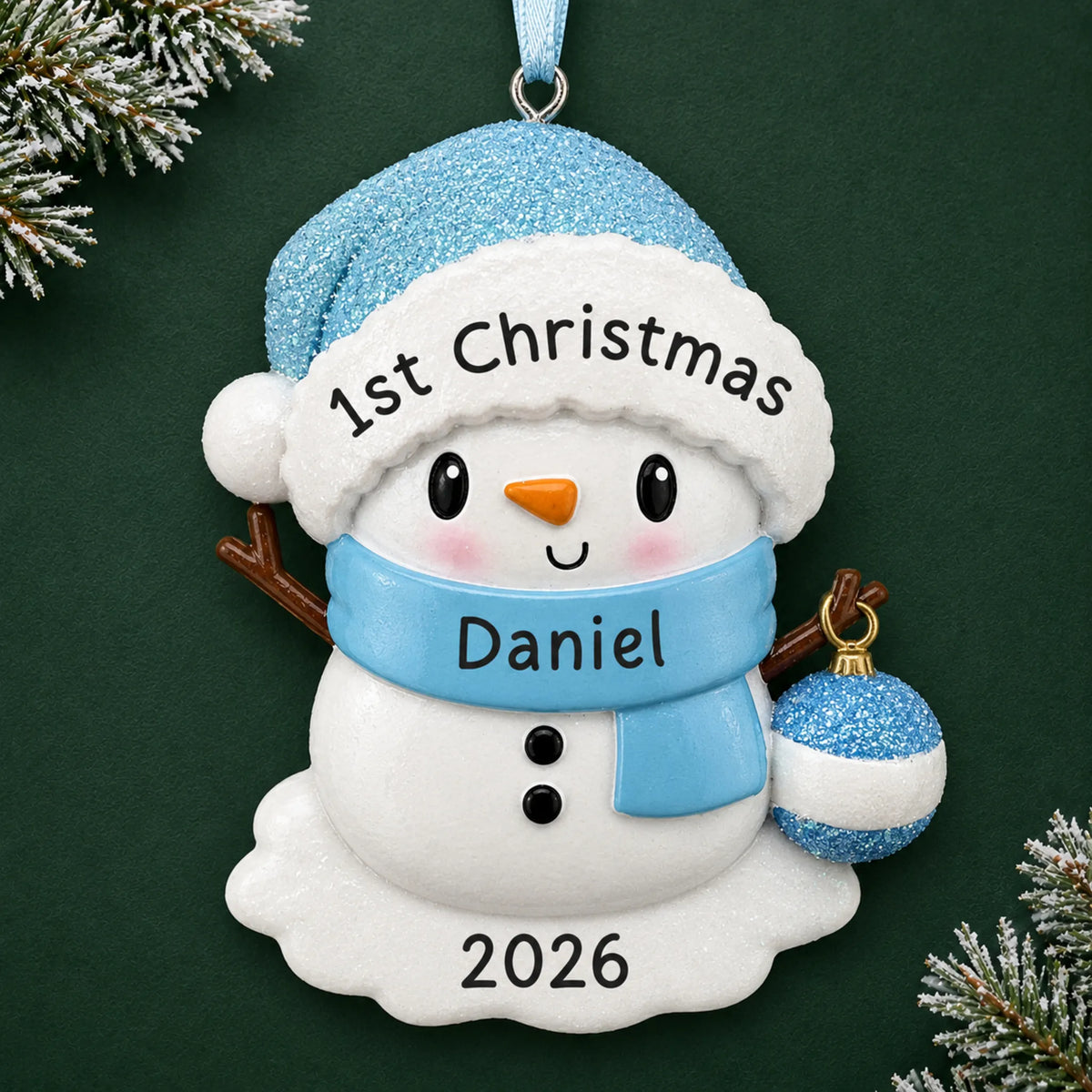 Personalized blue baby snowman christmas ornament on a dark green pine background