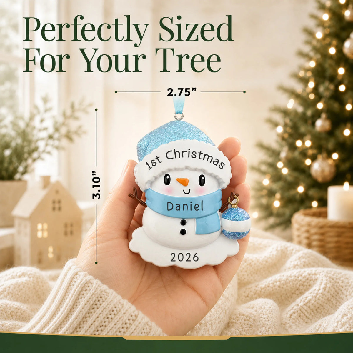 Size guide: the personalized blue baby snowman christmas ornament shown in hand next to a Christmas tree