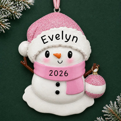 Personalized pink baby snowman christmas ornament on a dark green pine background