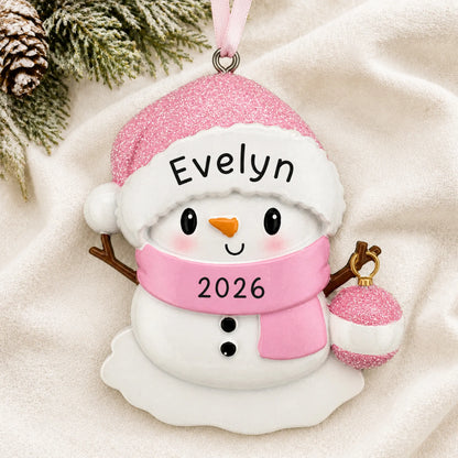 Personalized pink baby snowman christmas ornament laid on a soft white knit blanket
