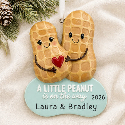 Personalized Little Peanut Expecting christmas ornament laid on a soft white knit blanket