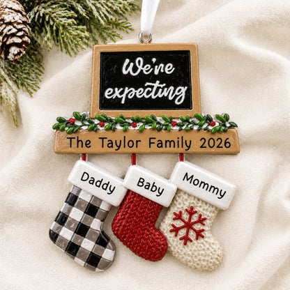 Personalized We're Expecting Couple's christmas ornament laid on a soft white knit blanket