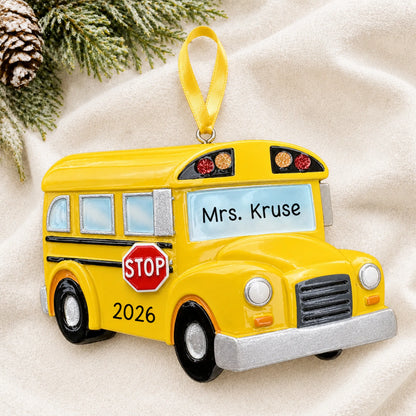 Personalized yellow school bus Christmas ornament shown on a soft white blanket