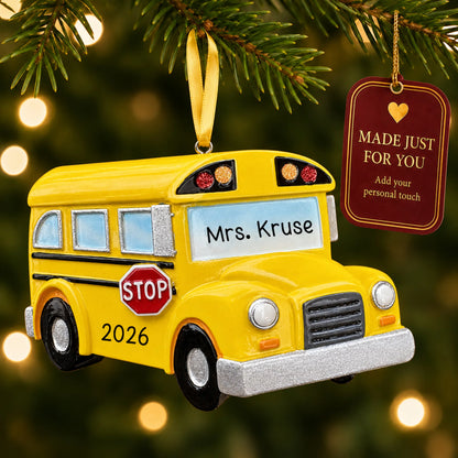 Personalized yellow school bus Christmas ornament hanging among tree lights with a Made Just For You tag