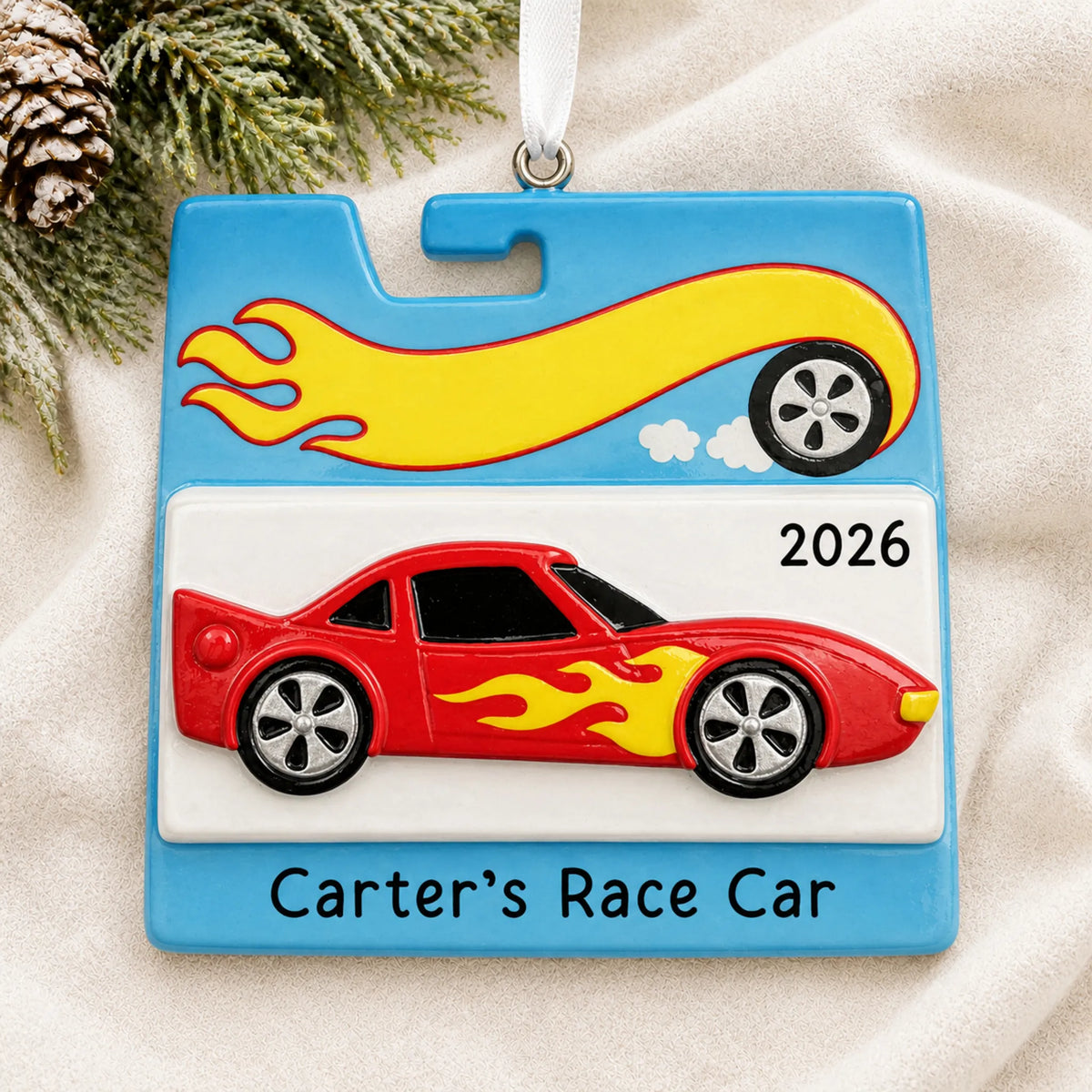Personalized race car christmas ornament laid on a soft white knit blanket