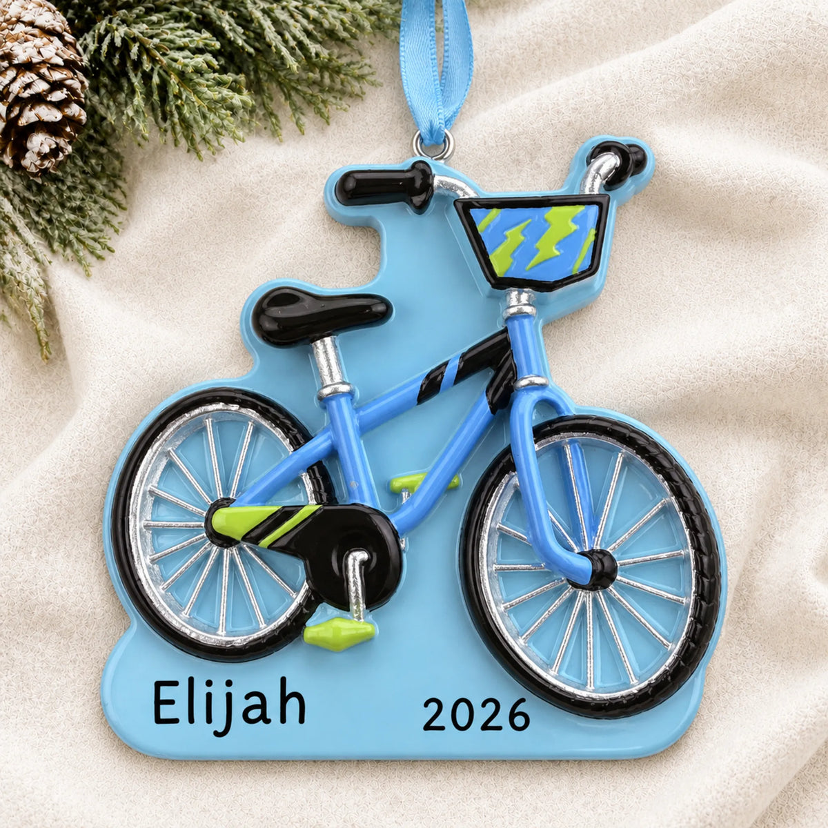 Personalized boy's first bike christmas ornament laid on a soft white knit blanket