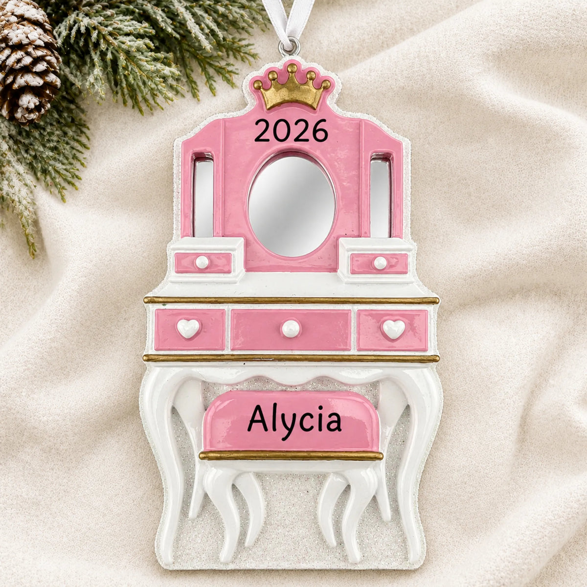 Personalized girls vanity mirror christmas ornament laid on a soft white knit blanket