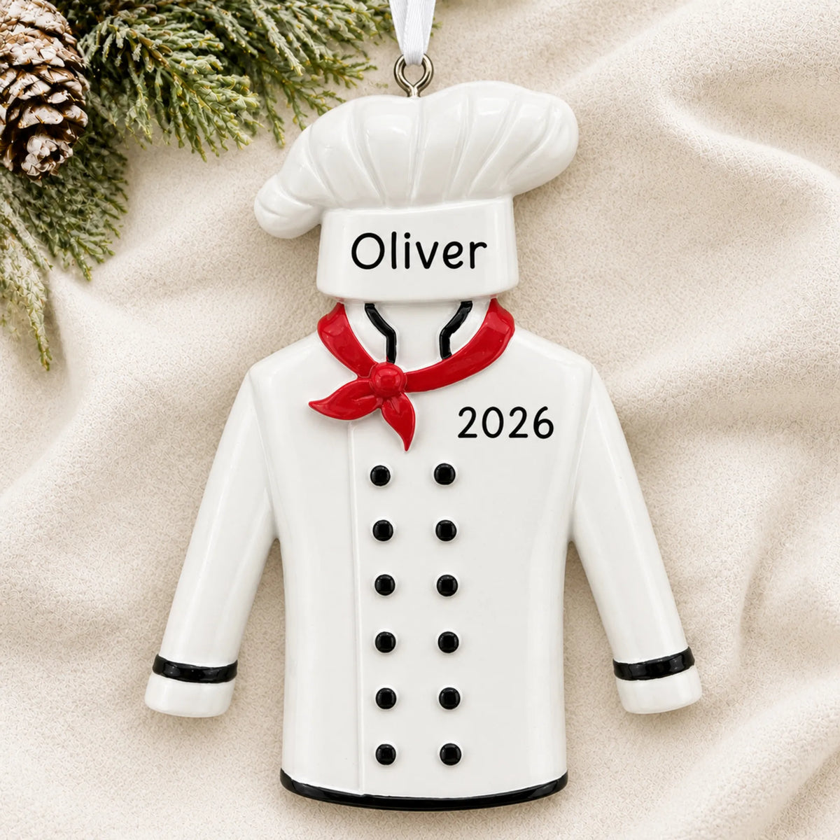 Personalized chef uniform christmas ornament laid on a soft white knit blanket
