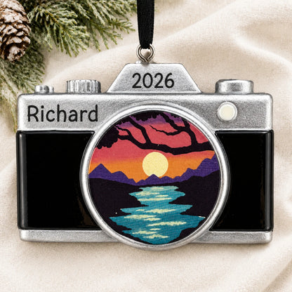 Personalized dslr camera christmas ornament laid on a soft white knit blanket