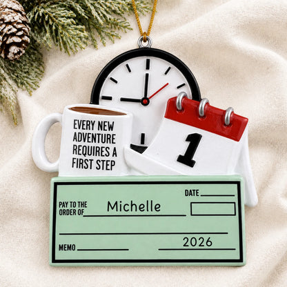 Personalized first job paycheck christmas ornament laid on a soft white knit blanket