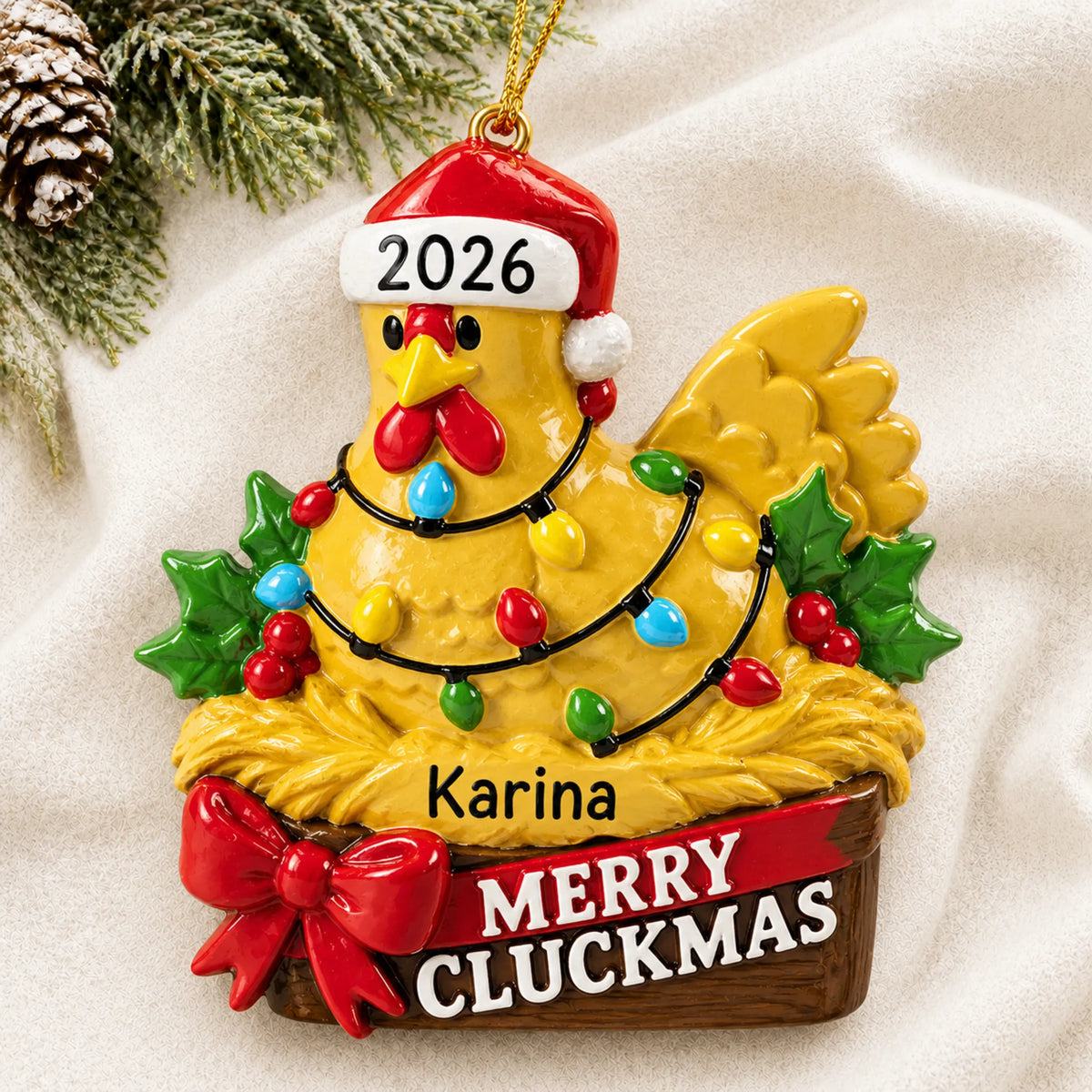 Personalized merry cluckmas chicken christmas ornament laid on a soft white knit blanket