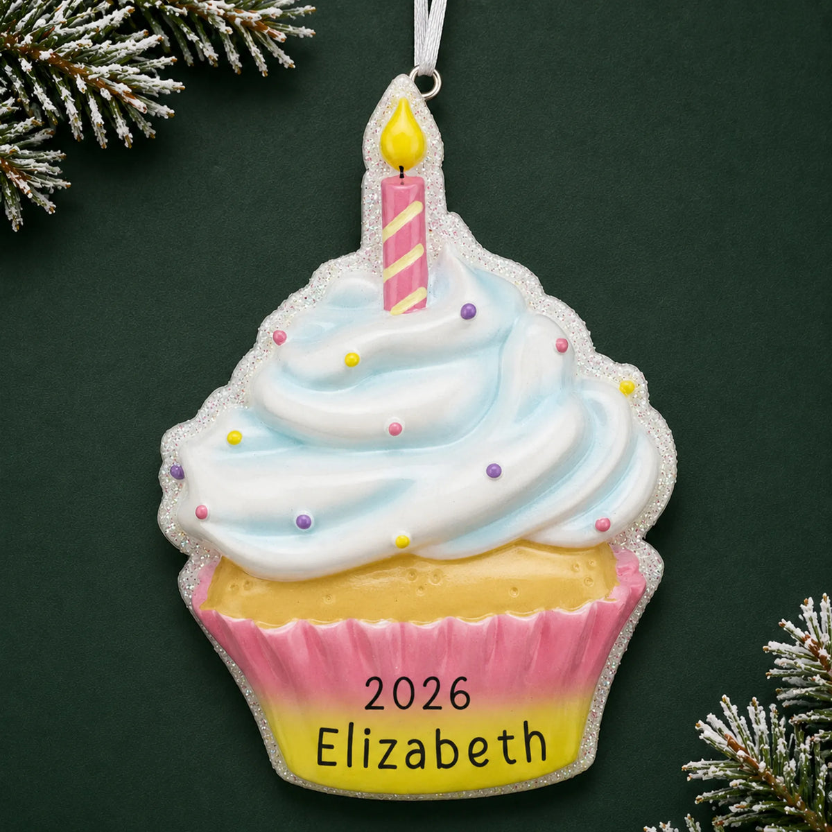 Personalized birthday cupcake christmas ornament on a dark green pine background