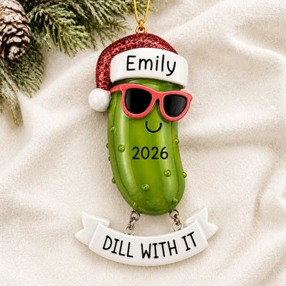Personalized Pickle christmas ornament laid on a soft white knit blanket