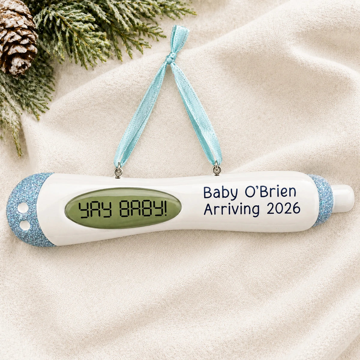 Personalized Pregnancy Test Baby Boy christmas ornament laid on a soft white knit blanket