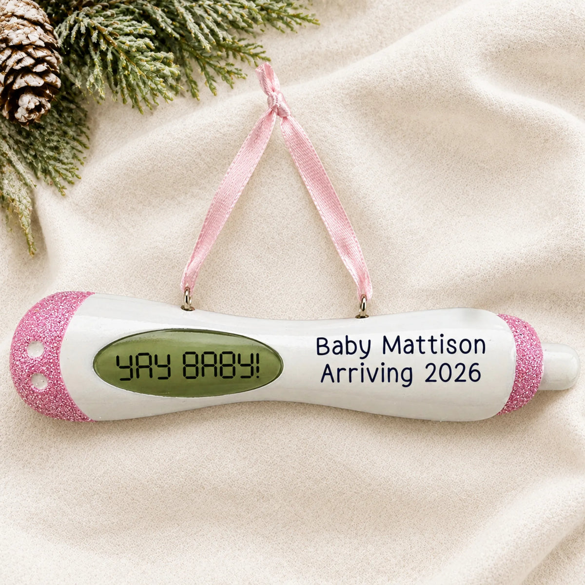Personalized Pregnancy Test Baby Girl christmas ornament laid on a soft white knit blanket