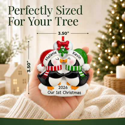 Size guide: the personalized penguin mistletoe kisses couple christmas ornament shown in hand next to a Christmas tree