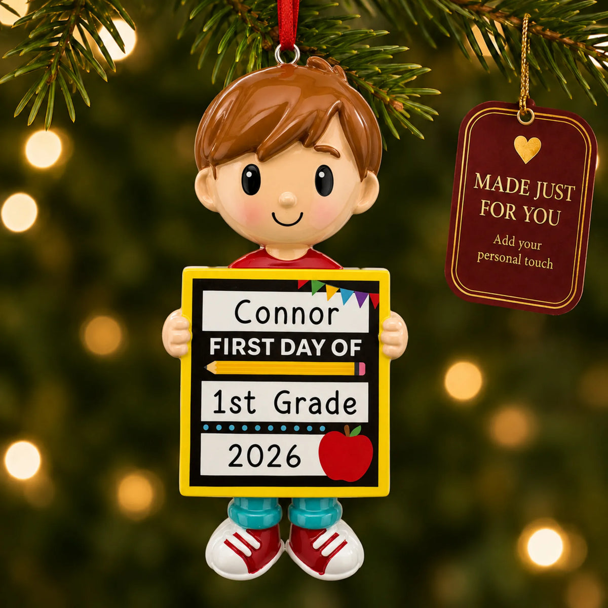 Personalized first day of school boy Christmas ornament hanging among tree lights with a Made Just For You tag