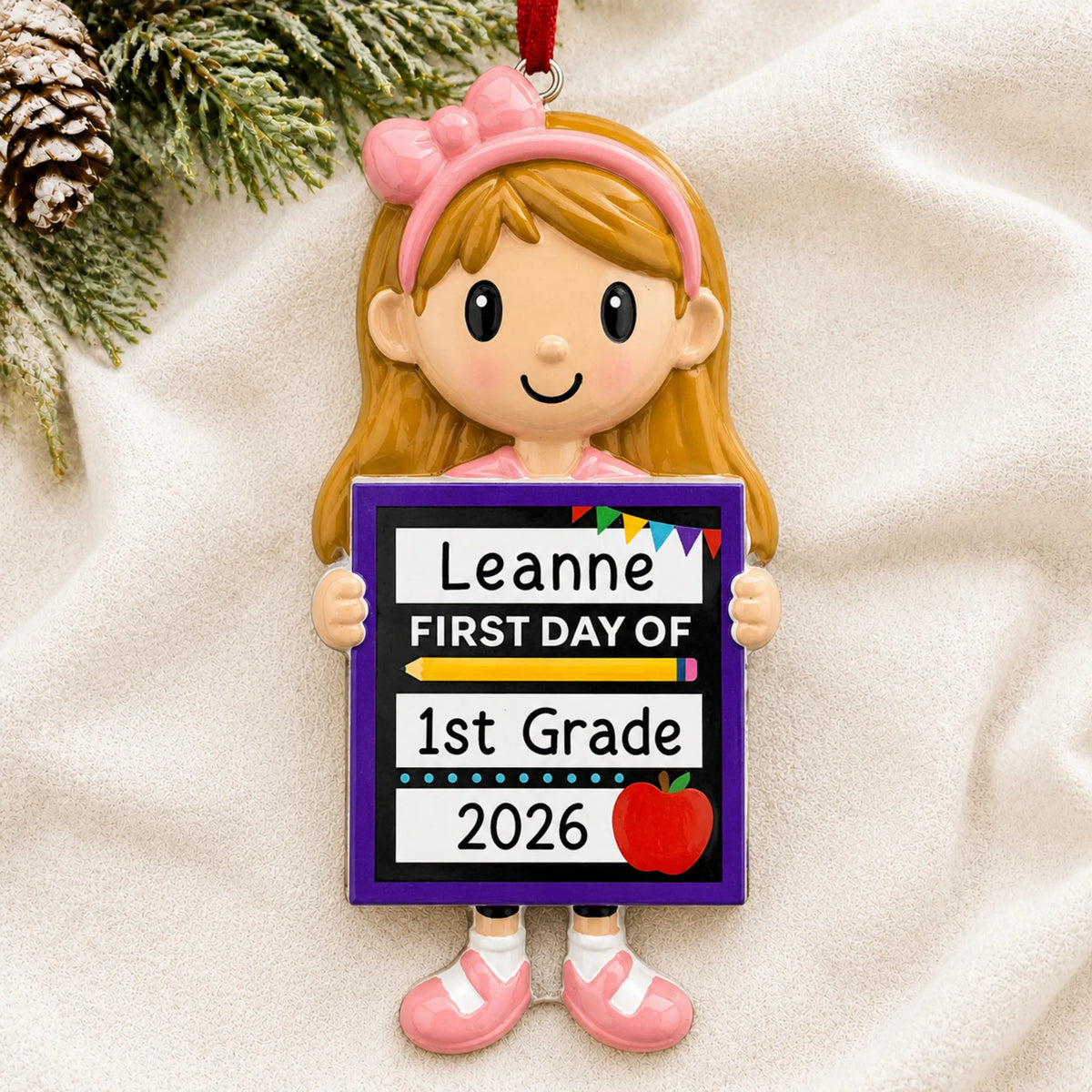 Personalized first day of school girl Christmas ornament shown on a soft white blanket