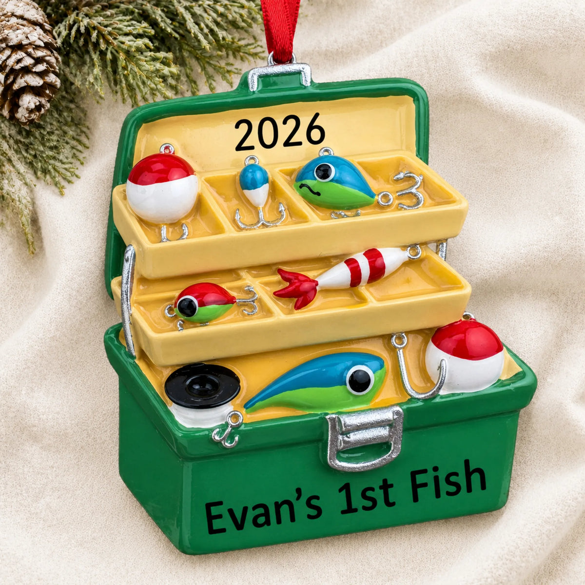 Personalized green fishing tackle box christmas ornament laid on a soft white knit blanket