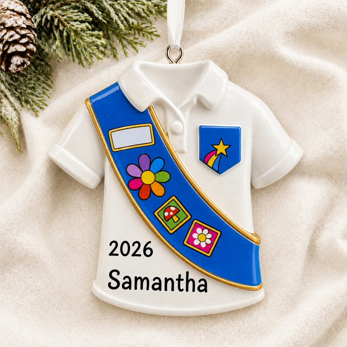 Personalized Girl Scout blue sash christmas ornament laid on a soft white knit blanket