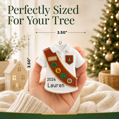 Size guide: the personalized Girl Scout brown sash christmas ornament is 3.50 in wide by 3.50 in tall, shown in hand