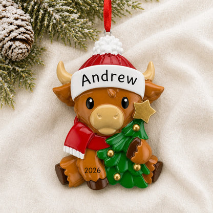 Personalized highland baby cow christmas ornament laid on a soft white knit blanket