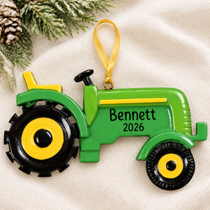 Personalized farm tractor christmas ornament laid on a soft white knit blanket