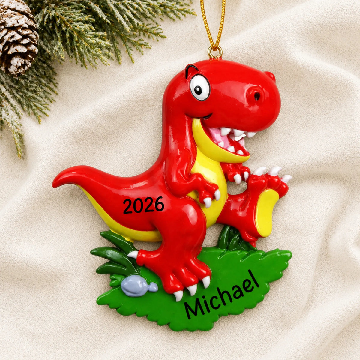 Personalized red t-rex christmas ornament laid on a soft white knit blanket