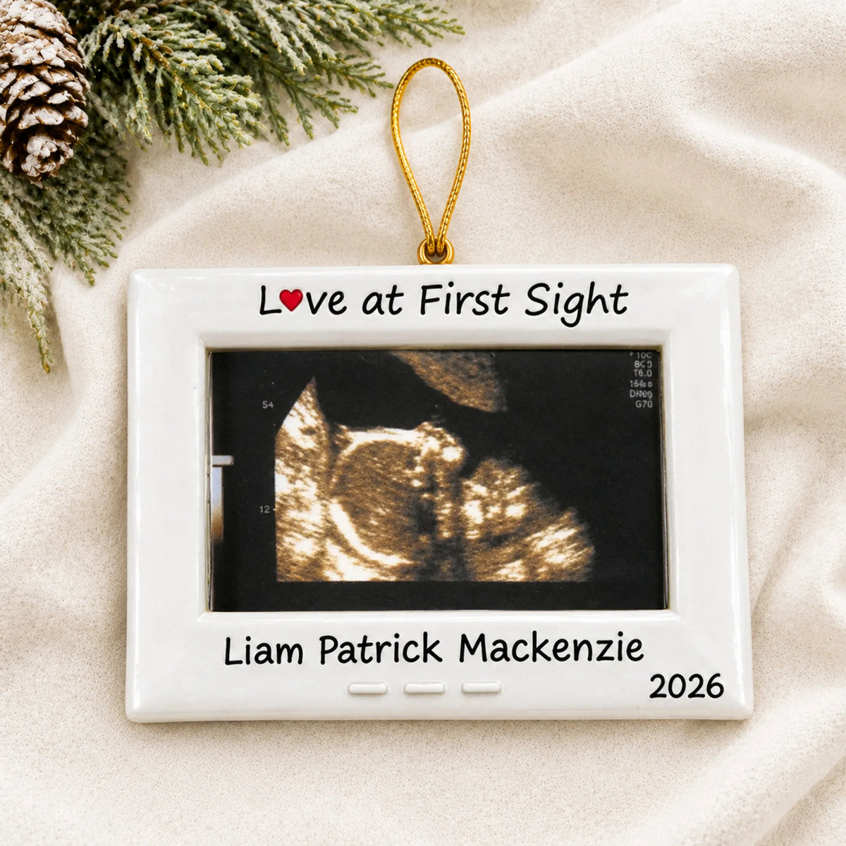 Personalized New Baby Ultrasound Frame christmas ornament laid on a soft white knit blanket