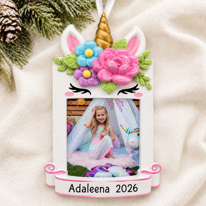 Personalized unicorn photo frame christmas ornament laid on a soft white knit blanket