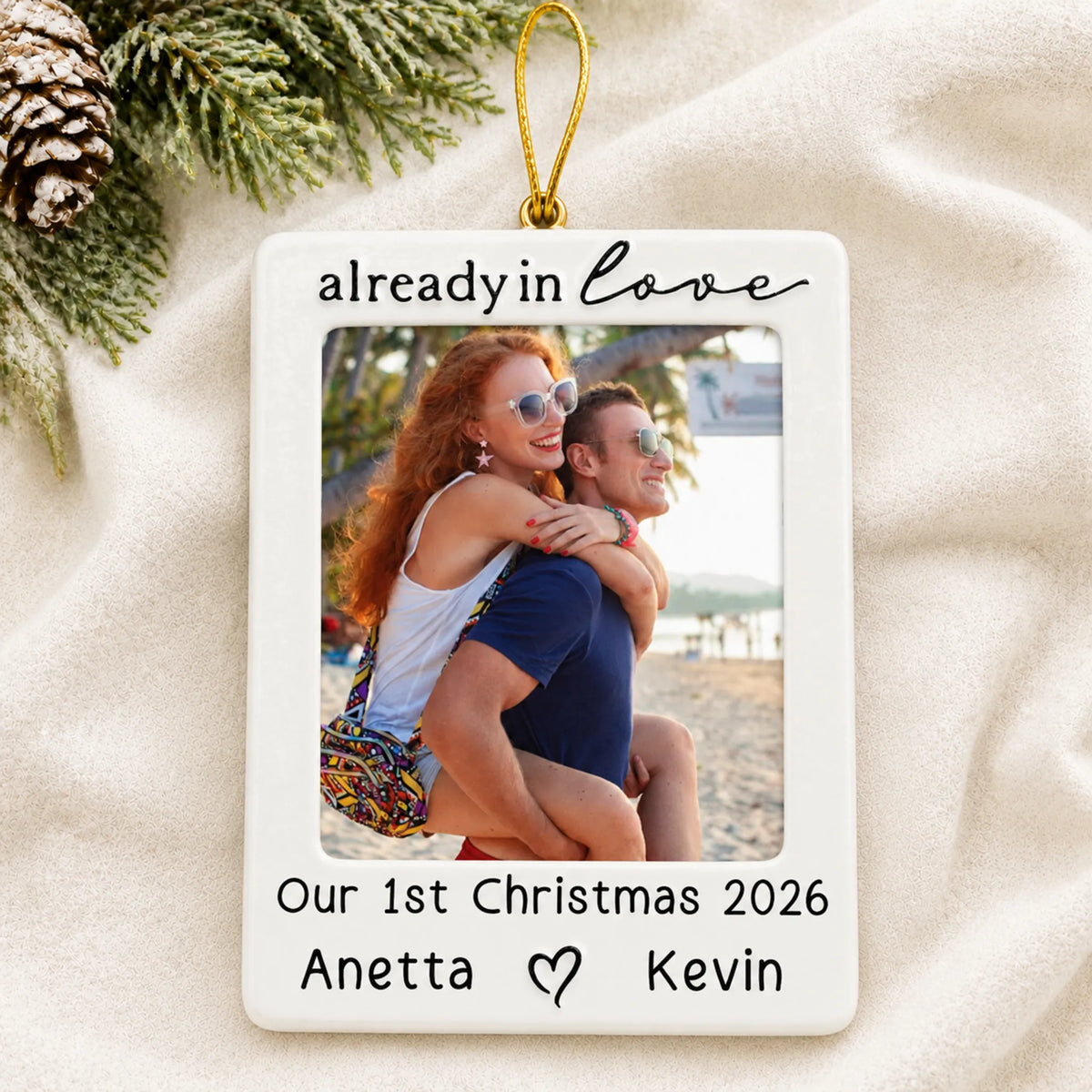 Personalized couple photo frame christmas ornament laid on a soft white knit blanket