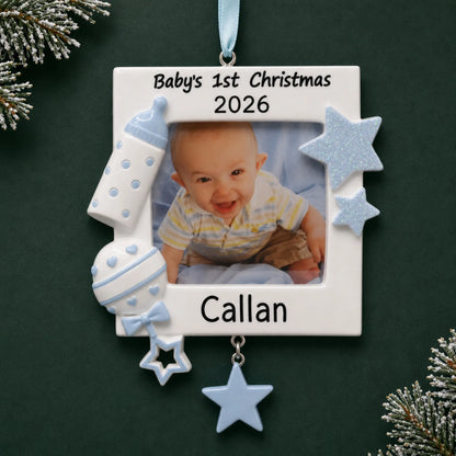 Personalized blue baby's first picture frame christmas ornament on a dark green pine background