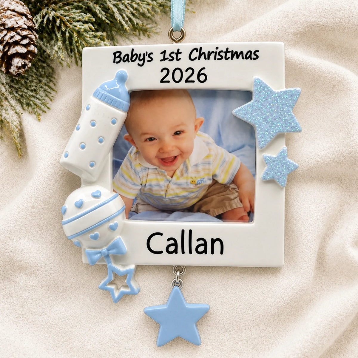 Personalized blue baby's first picture frame christmas ornament laid on a soft white knit blanket