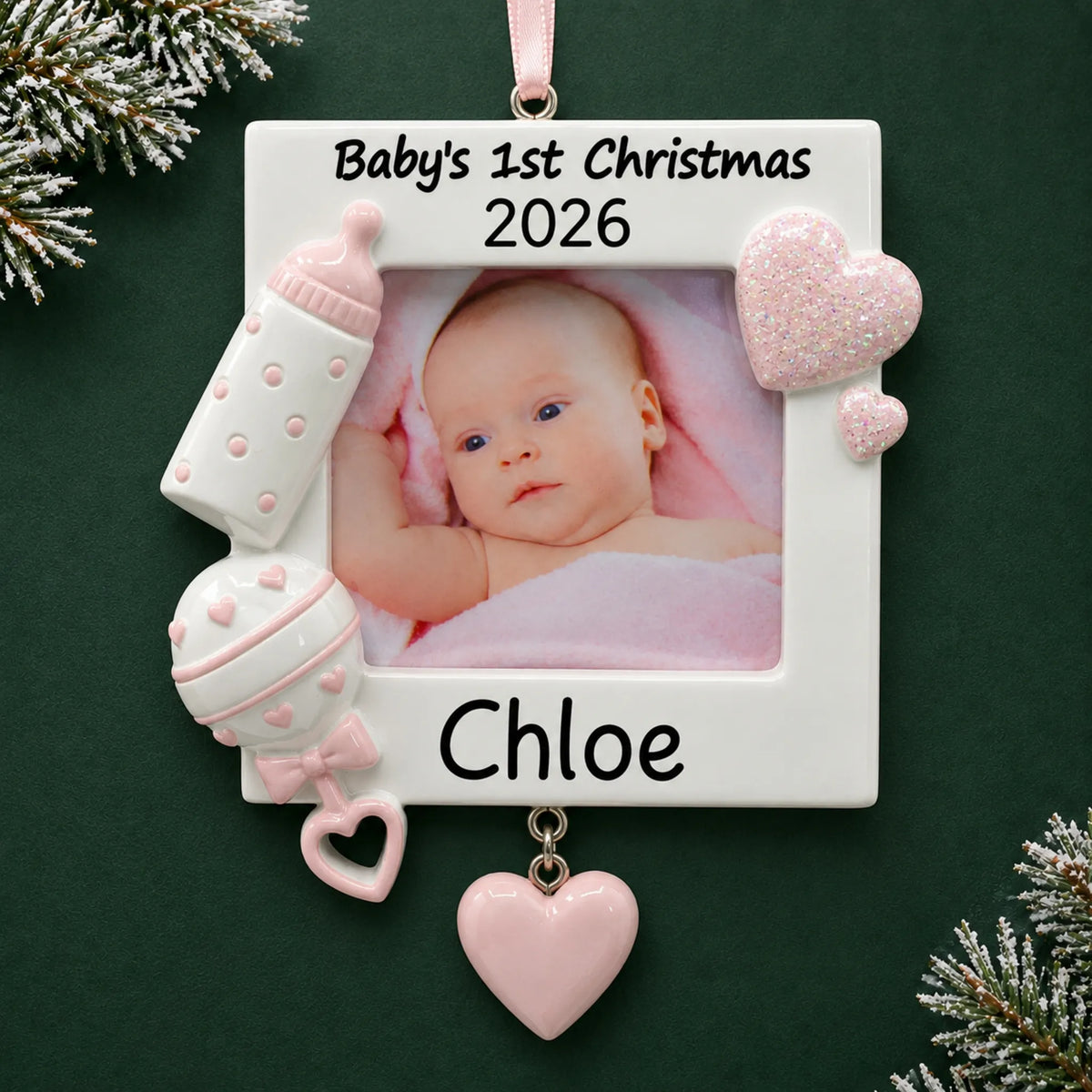 Personalized pink baby's first picture frame christmas ornament on a dark green pine background