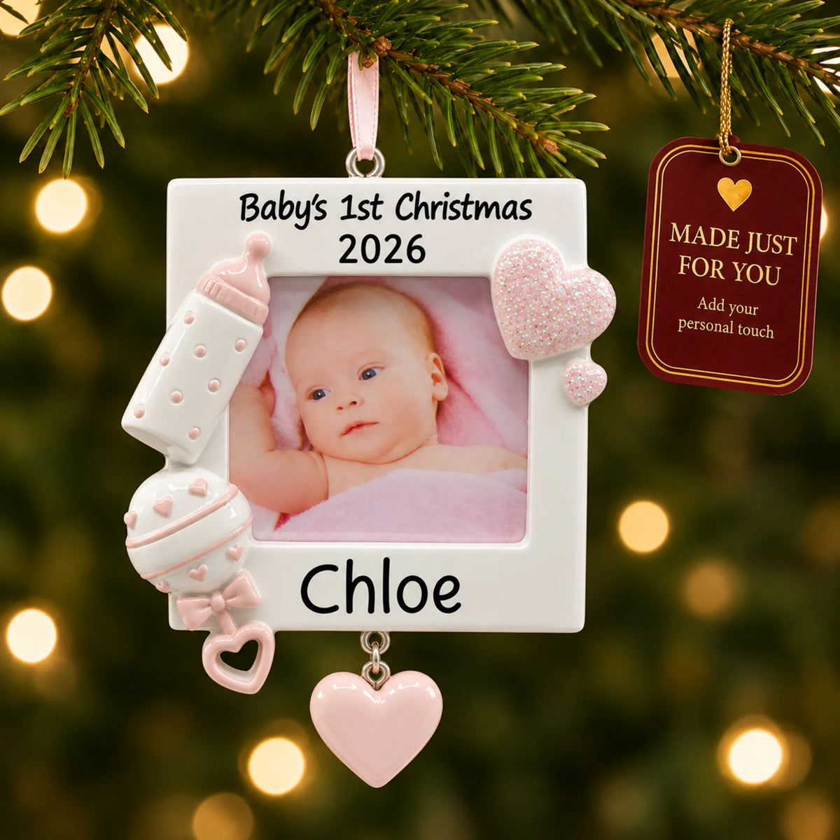 Pink baby's first picture frame christmas ornament hanging on a lit Christmas tree with a Made Just For You gift tag