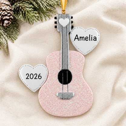 Personalized pink guitar christmas ornament laid on a soft white knit blanket
