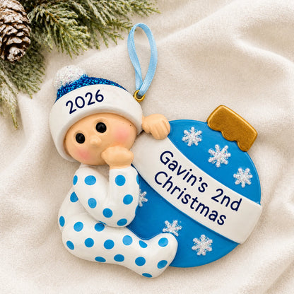 Personalized blue baby's 2nd christmas ornament laid on a soft white knit blanket