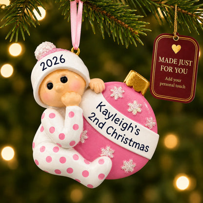 Pink baby's 2nd christmas ornament hanging on a lit Christmas tree with a Made Just For You gift tag