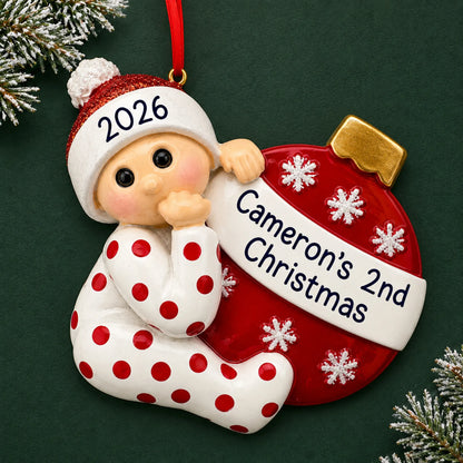 Personalized red baby's 2nd christmas ornament on a dark green pine background