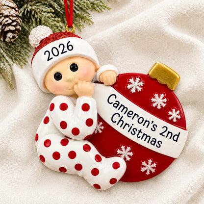 Personalized red baby's 2nd christmas ornament laid on a soft white knit blanket